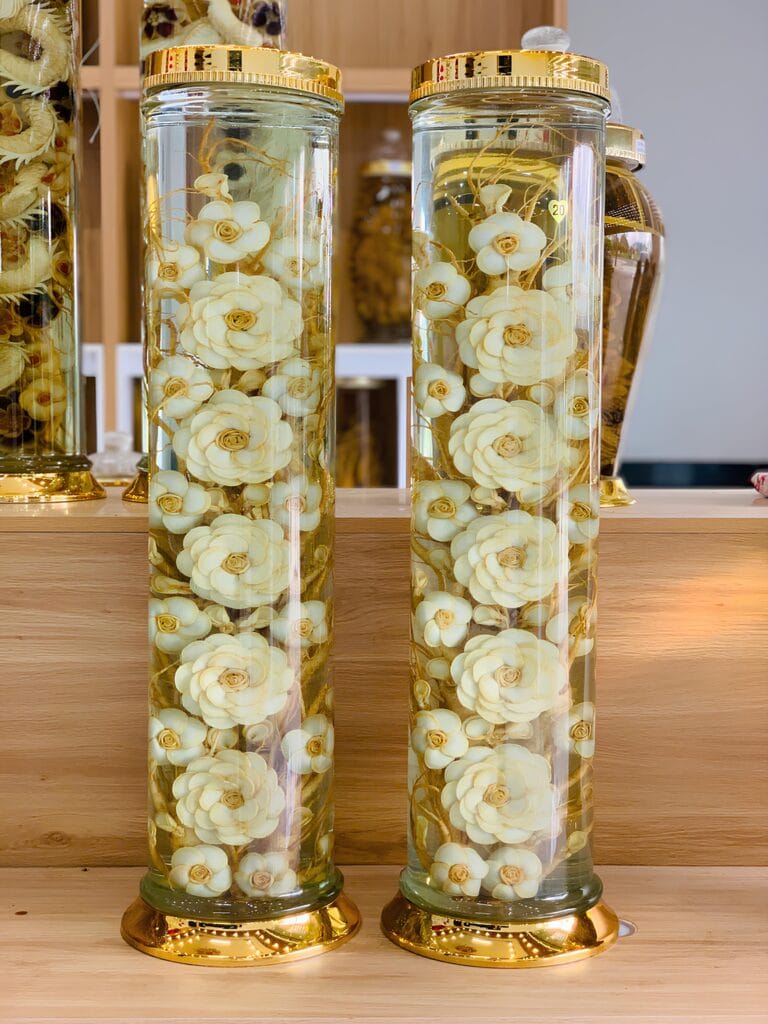 Bình hoa sâm trụ 20 lít kết tinh xảo 5 bông hoa lớn và 13 bông hoa nhỏ từ nhân sâm Hàn Quốc ngâm rượu men lá Hòa Bình 38 độ đẳng cấp.